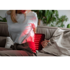 Person using a red light therapy device on their leg at home.