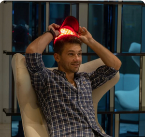 Man sitting in a chair holding a red lamp above his head in a modern room.